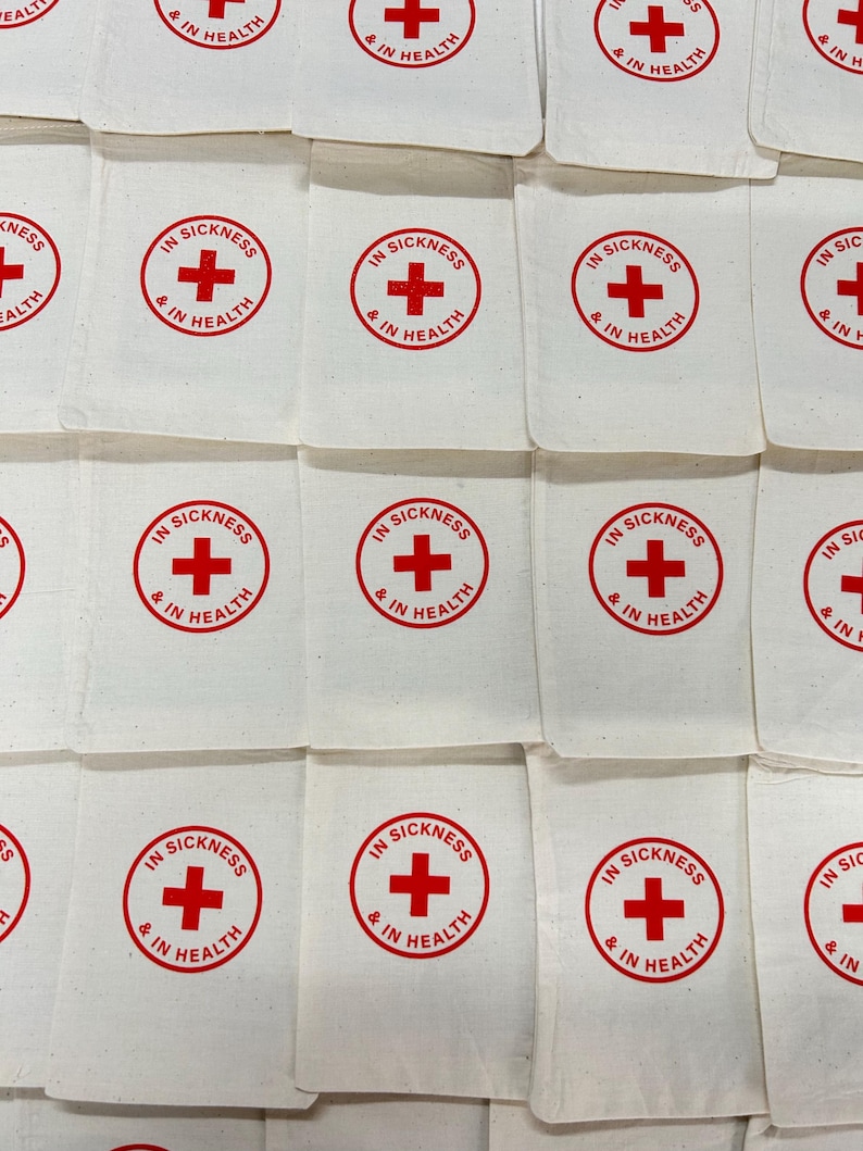 May include: White fabric pouches with a red cross symbol and the text "IN SICKNESS & IN HEALTH" printed in a circular design. The pouches are arranged in a grid pattern, creating a repetitive visual.