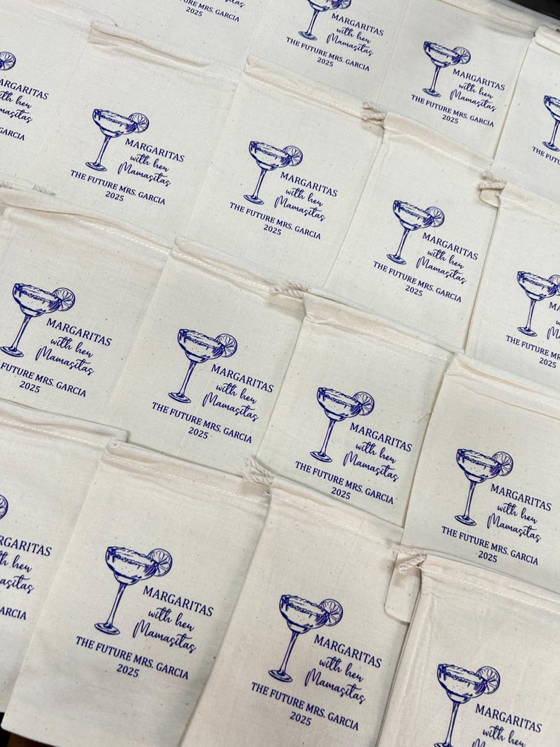 May include: Off-white drawstring bags with a blue margarita glass design and text that reads "MARGARITAS with her Mamasitas THE FUTURE MRS. GARCIA 2025". The bags are arranged in a grid pattern.