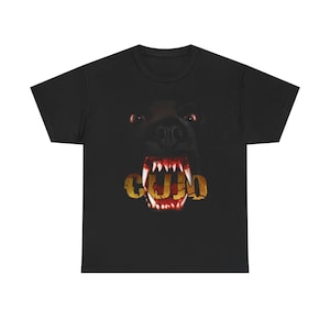 May include: Black t-shirt featuring a close-up of a snarling dog's face with the word "COLD" in gold letters across its teeth. The dog's eyes are red, and its teeth are sharp.