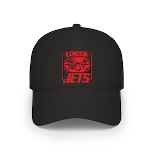 Puede incluir: Gorra de béisbol negra con el texto "LONDON JETS" en rojo y un gráfico de un avión a reacción. La gorra tiene una visera curva y una corona estructurada. Un accesorio deportivo clásico.