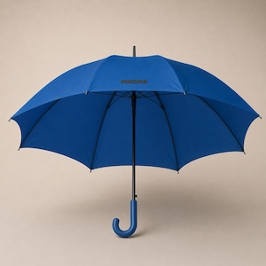 May include: Open blue umbrella with a curved handle. The umbrella has a black shaft and a blue canopy. The word "macma" is printed on the canopy. The umbrella is open and displayed against a neutral background.