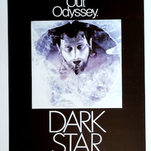 May include: A vintage movie poster for "Dark Star" features a man's face emerging from a misty background. The title "DARK STAR" is prominently displayed in white, bold lettering below the image. The text "The Spaced Out Odyssey" is at the top.