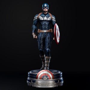 Op de afbeelding: Een Captain America-beeld in een dynamische pose, gekleed in een blauw-wit kostuum, met een schild. Het beeld heeft een bruine riem en banden. De basis toont het Captain America-schild en de tekst "CAPTAIN AMERICA THE WINTER SOLDIER."