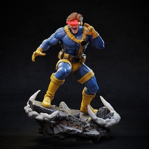 May include: A detailed figurine of a superhero in a dynamic pose. The figure is clad in a blue and yellow costume, with a red visor. It stands on a rocky base with a cloud-like effect. The character is mid-action, with an open mouth and raised arm.
