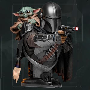 May include: A detailed bust of The Mandalorian holding a blaster, with Grogu perched on his shoulder. The Mandalorian is clad in silver armor with a black cape. Grogu is wrapped in a brown cloth. The bust is a collectible item from the Star Wars franchise.