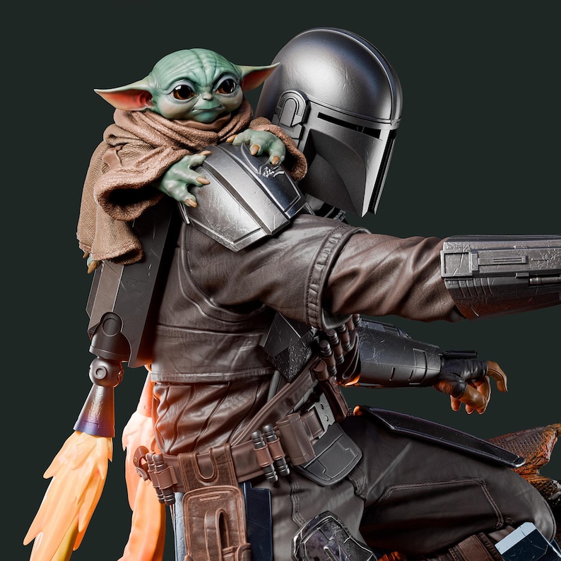 May include: A detailed figurine of The Mandalorian with Grogu. The Mandalorian is wearing a silver helmet and brown armor. Grogu, with green skin and large ears, is perched on his shoulder. A jetpack with orange flames is attached to the Mandalorian's back.