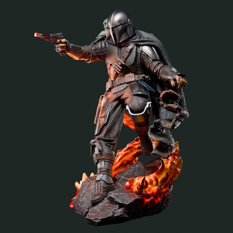 May include: A detailed statue of a character in dark armor, holding a blaster with a red light. The figure stands on a rocky base with fiery orange and yellow accents. The character wears a helmet and cape, with a detailed belt and pouches.