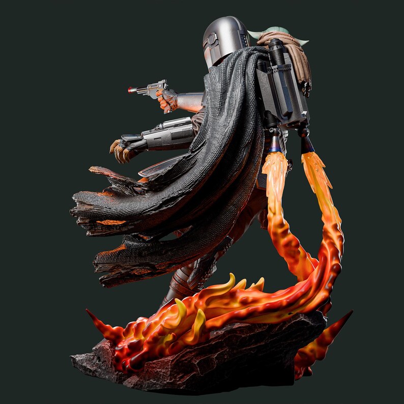 May include: A detailed statue of a Mandalorian figure with a blaster, cape, and jetpack, with Grogu on his back. The figure is standing on a fiery base with orange and yellow flames. The Mandalorian is wearing silver armor and a black cape.