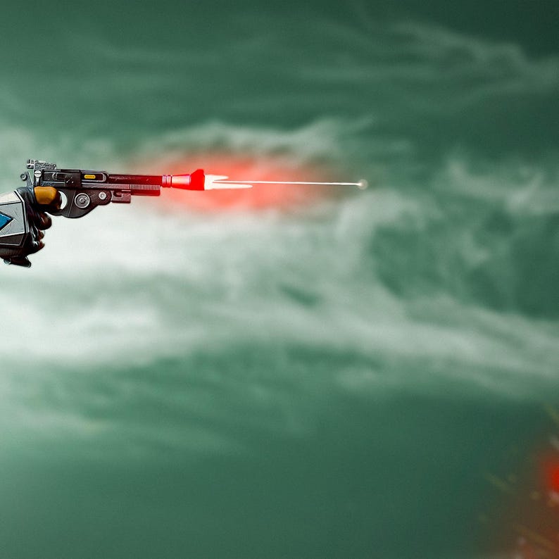 May include: A futuristic ray gun with a red laser beam firing from the barrel. The gun is held by a gloved hand against a cloudy, green background. The gun has a black, silver, and yellow design.