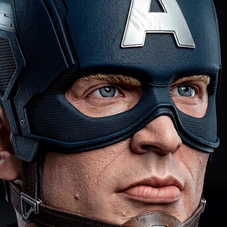 Op de afbeelding: Close-up van een Captain America-buste. De buste heeft een blauwe helm met een zilveren "A"-embleem en een zwart masker. Het personage heeft blauwe ogen en blonde wenkbrauwen. De buste is gedetailleerd met realistische huidtinten en texturen.