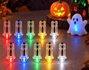 May include: Ten small, clear cylindrical LED lights arranged in two rows, each emitting a distinct red, blue, green, yellow, or white glow. In the background, a glowing orange jack-o'-lantern, a miniature haunted house, and a white ghost.