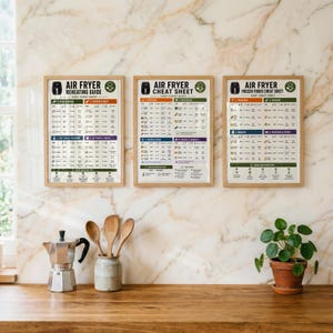 Pode incluir: Três quadros de parede emoldurados intitulados Air Fryer Reheating Guide, Air Fryer Cheat Sheet e Air Fryer Frozen Foods Cheat Sheet. Cada quadro apresenta colunas organizadas com ícones, categorias de alimentos, temperaturas e tempos de cozedura para fritadeira de ar.