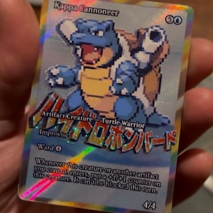 Peut inclure: Une carte à collectionner holographique représentant une créature bleue pixelisée ressemblant à une tortue avec des canons sur le dos. La carte est intitulée "Kappa Cannoneer" et contient du texte japonais et des instructions de jeu. La carte est 4/4.
