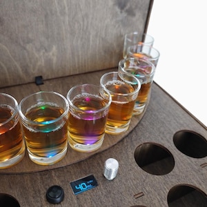 Könnte beinhalten: Holz-Shotglas-Serviertablett mit sechs Shotgläsern, die mit bernsteinfarbener Flüssigkeit gefüllt sind. Das Tablett hat ein digitales Display mit der Anzeige "40ml" und einen Drehknopf. Die Shotgläser sind mit bunten Lichtern beleuchtet.