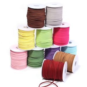 May include: A collection of eleven spools of flat faux suede cord in various colors including brown, gray, yellow, lime green, hot pink, light pink, olive green, purple, light blue, tan, and deep red, arranged in a stacked pyramid formation.