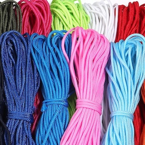 Puede incluir: Una colección de cordones de nailon multicolor dispuestos en haces ordenados. El surtido incluye tonos vibrantes de verde oscuro, rosa fuerte, verde lima, blanco, rojo, azul marino, azul real, rosa claro, azul claro y cuerda trenzada naranja.