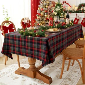May include: A rectangular dining table covered with a red, green and black plaid tablecloth. The table is surrounded by wooden chairs, each featuring a large red fabric bow tied to the backrest, creating a coordinated holiday dining arrangement.