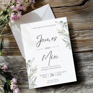 May include: A white wedding invitation card with a matching envelope, featuring green watercolor eucalyptus leaf illustrations, black serif and script text reading James and Mia, Sunday April 26 2 O'clock 202X, and Lily Falls Estate 150 Earth Lane, NY.