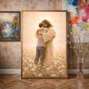 May include: A framed painting depicts two figures embracing in a field of white flowers. One figure is wearing a white robe, the other a light-colored shirt and jeans. The painting has a warm, soft color palette.