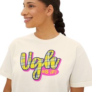 May include: Cream-colored t-shirt with the text "Ugh as If!" in a bubble letter style. The text is outlined in pink with a yellow and blue plaid pattern inside the letters. The shirt is a casual, everyday wear item.