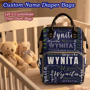 May include: A navy blue diaper bag with the name "Wynita" printed in white and green. The bag has a top handle and multiple pockets. The text "Custom Name Diaper Bags" and "Let's Customize Your Own Bag!" are at the top.