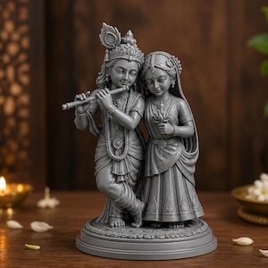 May include: A grey monochromatic statue of two figures standing together on a circular base. The figure on the left plays a flute and wears a peacock feather in their hair, while the figure on the right holds a lotus flower in their hands.