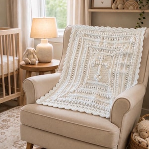 May include: A rectangular off-white crochet blanket featuring a central cross motif created with raised bobble stitches. The blanket has a textured pattern of alternating rows of stitches and a decorative scalloped edge border in a matching cream color.
