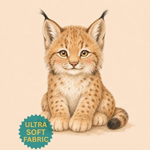 Op de afbeelding: Een digitale illustratie van een lynx-kitten met een beige vacht, donkerbruine vlekken en pluizige oren. Het kitten heeft grote amberkleurige ogen en een klein roze neusje. Een blauwgroene stervormige badge bevat de tekst ULTRA SOFT FABRIC.