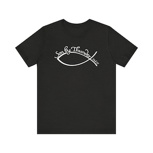 May include: Black t-shirt with the text "Son by Thunder" in a white, cursive font, along with a white fish symbol. The text "Mark 3:17" is also included in white.