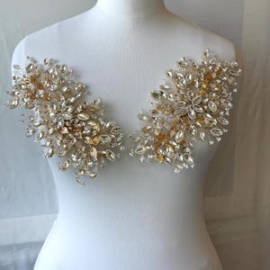 May include: Two symmetrical decorative appliqués featuring clear crystal rhinestones and gold-toned metallic leaves arranged in a branching, floral-inspired pattern on thin, flexible wire stems, designed for attachment to garments or accessories.