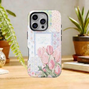 Puede incluir: Funda de teléfono floral con diseño de patchwork. Presenta tulipanes rosas, estampados florales y la cita: «Sé amable, ten coraje y cree siempre en un poco de magia». La funda tiene una mezcla de colores pastel.