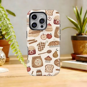 May include: A phone case with a cream-colored background featuring a repeating pattern of baking-related illustrations. The design includes apples, cinnamon sticks, flour bags, pie, bread, and jars of jam. The case has a glossy finish and a camera cutout.