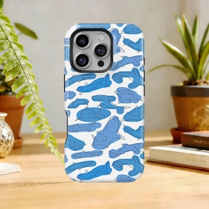 以下が含まれることがあります： 青いサメのイラストが繰り返される模様の白いスマートフォンケース。ハンマーヘッドシャークなど、さまざまな種類のサメが描かれています。ケースは光沢仕上げで、スマートフォン向けに設計されています。