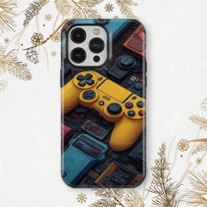 May include: A phone case featuring a vibrant yellow game controller design. The case is surrounded by a collage of retro gaming devices in various colors, including red, blue, and black. The case has a glossy finish and is designed to fit a smartphone.