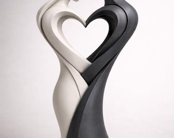 May include: A modern sculpture depicting two figures embracing, forming a heart shape. One figure is white, the other is dark gray. The sculpture is a symbol of love and unity, with smooth, flowing lines.