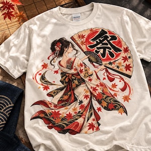 以下が含まれることがあります： クリーム色の半袖Tシャツ。柄入りの着物を着た人物が、赤い紅葉と祭という漢字が黒いインクで描かれた大きな扇子を持っているグラフィックイラストが中央にプリントされています。