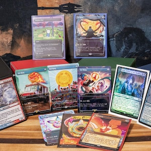 May include: A collection of Magic: The Gathering trading cards, featuring various colorful illustrations and designs. Cards are displayed with protective sleeves and storage boxes, showcasing fantasy art and game elements.