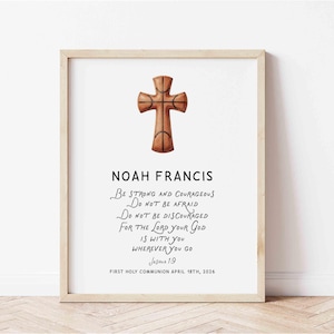 Op de afbeelding: Een ingelijste print met een houten kruisontwerp, dat lijkt op een basketbal. De print toont de naam "NOAH FRANCIS" en een religieus citaat uit Jozua 1:9. De tekst is in zwart script op een witte achtergrond, met de datum "APRIL 18TH, 2026" onderaan.