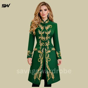 May include: A long, emerald green coat with gold embroidered floral designs. The coat features a high collar, long sleeves, and a tailored fit. The text "savage wardrobe" is visible at the bottom of the coat.