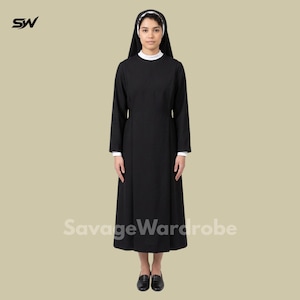 May include: A black nun's habit with a white collar and cuffs. The long-sleeved dress is floor-length and worn with a white head covering and black shoes. The SavageWardrobe logo is visible.