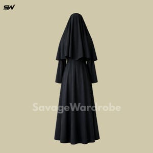 May include: A long, black dress with a matching head covering. The dress has long sleeves and a full skirt. The head covering drapes over the shoulders. The text "SavageWardrobe" is printed on the bottom of the dress.