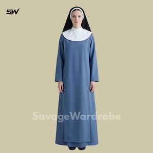 Puede incluir: Un hábito azul de cuerpo entero con mangas largas y cuello alto. La prenda incluye una pieza de cuello blanca y un tocado negro que enmarca el rostro. El diseño es sencillo, de color sólido y cuenta con una falda estructurada hasta el suelo.
