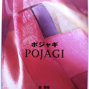 Op de afbeelding: Een boekomslag met de titel "POJAGI" in grote zwarte letters. De omslag heeft een roze en paars patchwork-ontwerp met tekst in het Japans en Engels, waaronder "KOREAN PATCHWORK."
