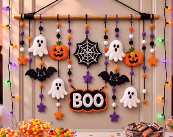 Könnte beinhalten: Ein Halloween-Wandbehang mit einem Holzstab und daran hängenden gehäkelten Ornamenten, darunter weiße Geister, orangefarbene Kürbisse, schwarze Fledermäuse, violette und orangefarbene Sterne, ein schwarzes Spinnennetz und ein Schild mit der Aufschrift BOO.