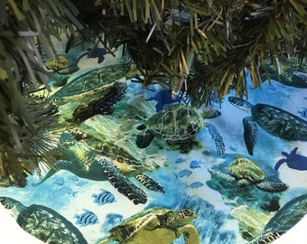 May include: A blue and green Christmas tree skirt with a sea turtle and fish design.