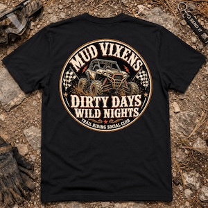 Könnte beinhalten: Ein schwarzes Kurzarm-T-Shirt mit einer kreisförmigen Grafik auf der Rückseite. Das Design zeigt ein Geländefahrzeug mit dem Text MUD VIXENS, DIRTY DAYS WILD NIGHTS und TRAIL RIDING SOCIAL CLUB, ergänzt durch Zielflaggen und Sterne.