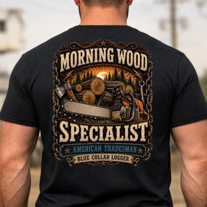 Pode incluir: Uma t-shirt preta com um gráfico nas costas contendo o texto MORNING WOOD SPECIALIST, AMERICAN TRADESMAN e BLUE COLLAR LOGGER. O design inclui uma motosserra, um machado e troncos empilhados contra um fundo de floresta ao pôr do sol.