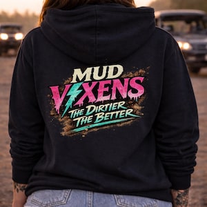 Op de afbeelding: Zwarte hoodie met de tekst "MUD VIXENS THE DIRTIER THE BETTER" in een kleurrijk ontwerp. De tekst is in wit, roze en teal, met een bliksem graphic. De hoodie is donker van kleur.