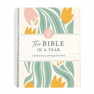 May include: A spiral-bound book titled "The Bible in a Year" with a floral design. The cover features a cream background with illustrations of pink and yellow flowers and green leaves. The text "The Bible in a Year" is in a script font.
