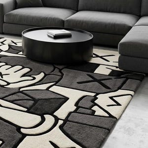 May include: A modern living room featuring a gray sectional sofa, a black round coffee table, and a patterned area rug. The rug has a repeating design in black, white, and gray.